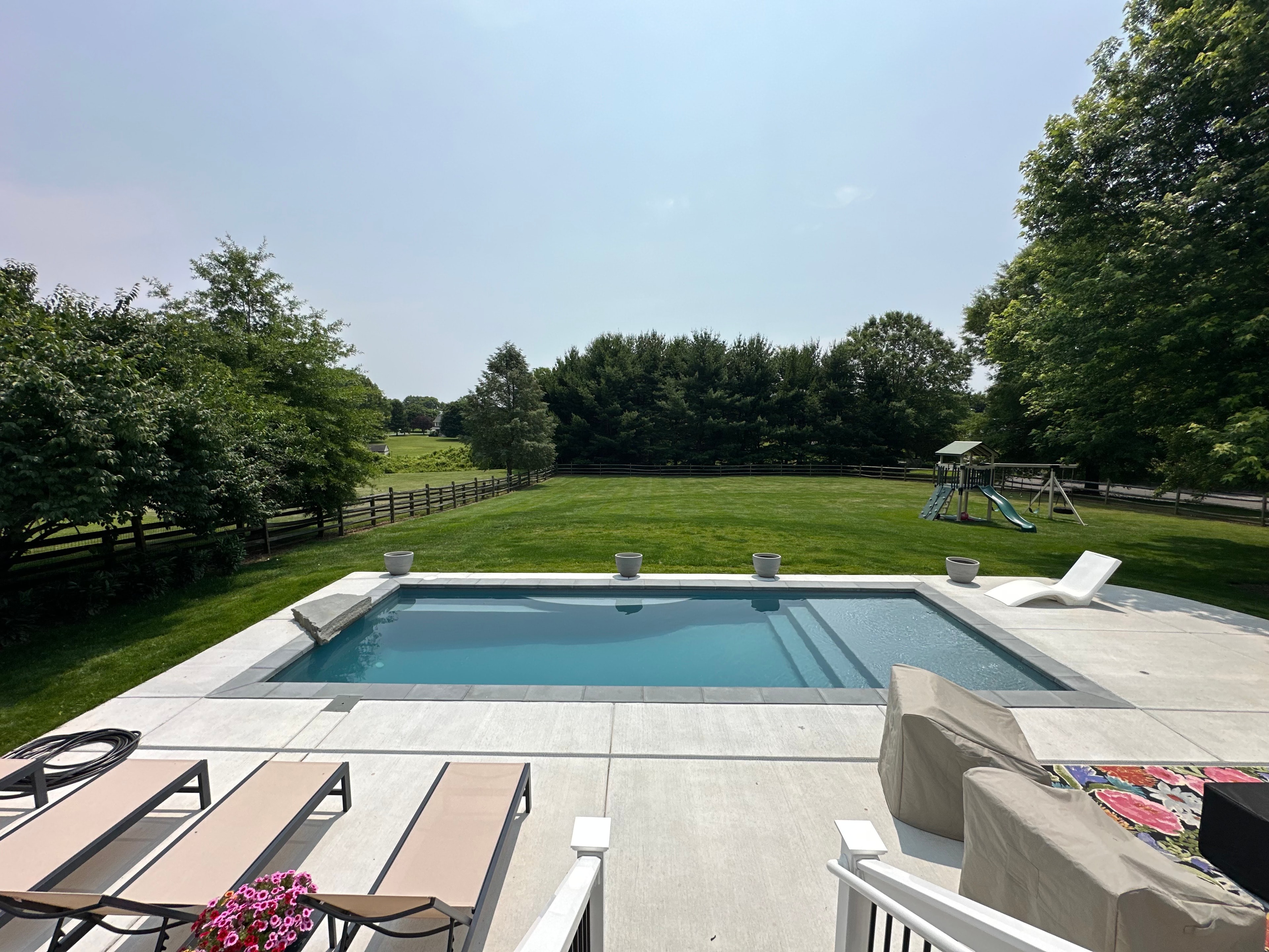 LandPro aerial daytime shot of pool with concrete surround and playground