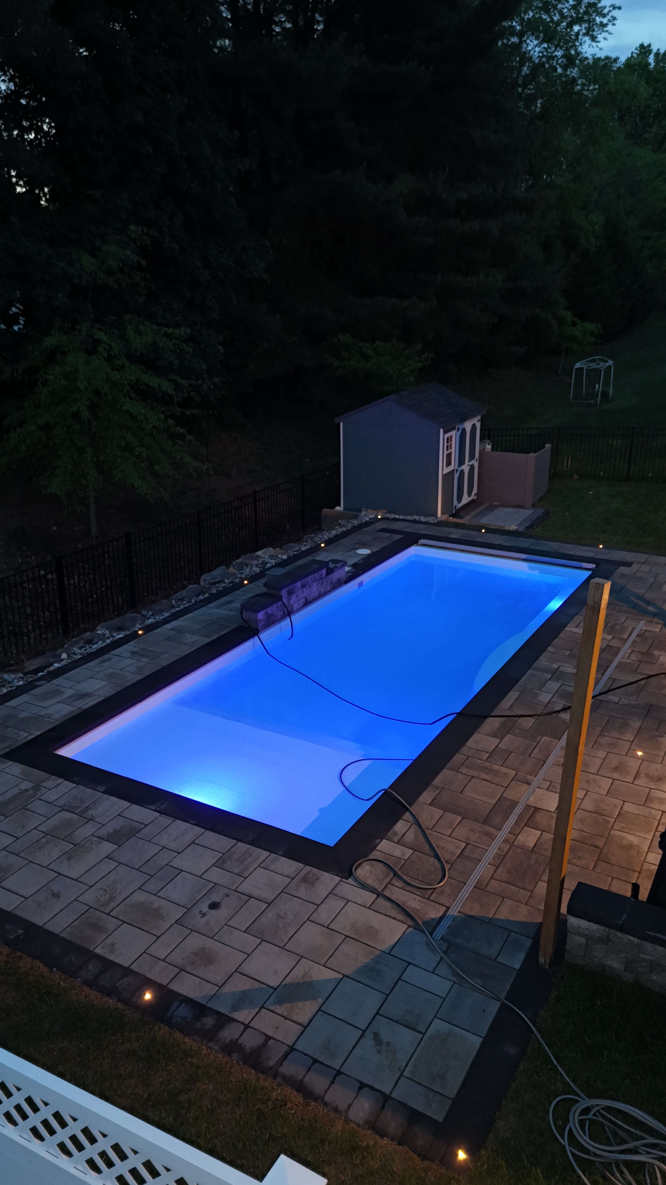 LandPro aerial pool shot glowing blue at night with paver surround