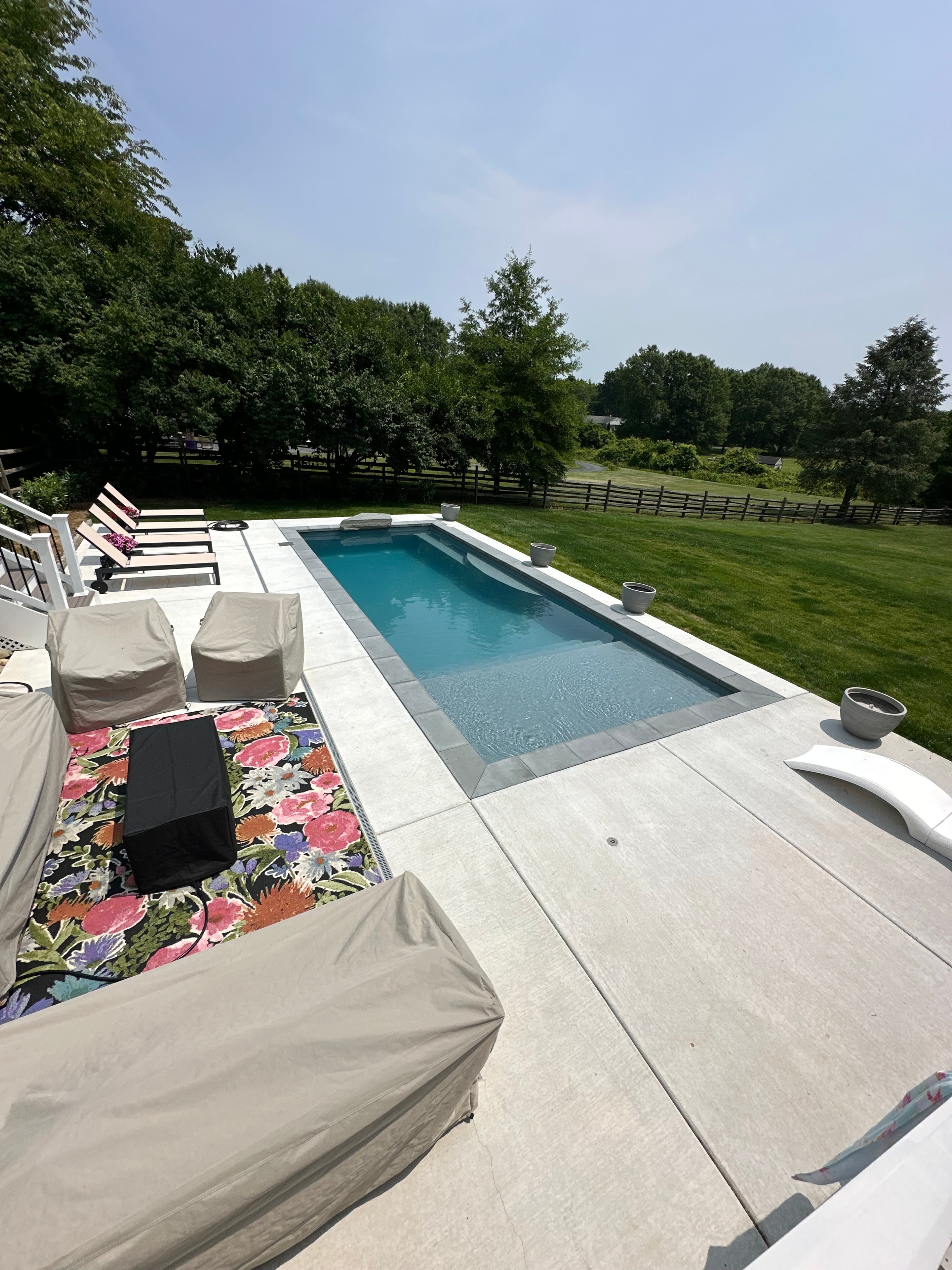 Backyard for the Kids — poolside view with patio furniture and open lawn beyond fence