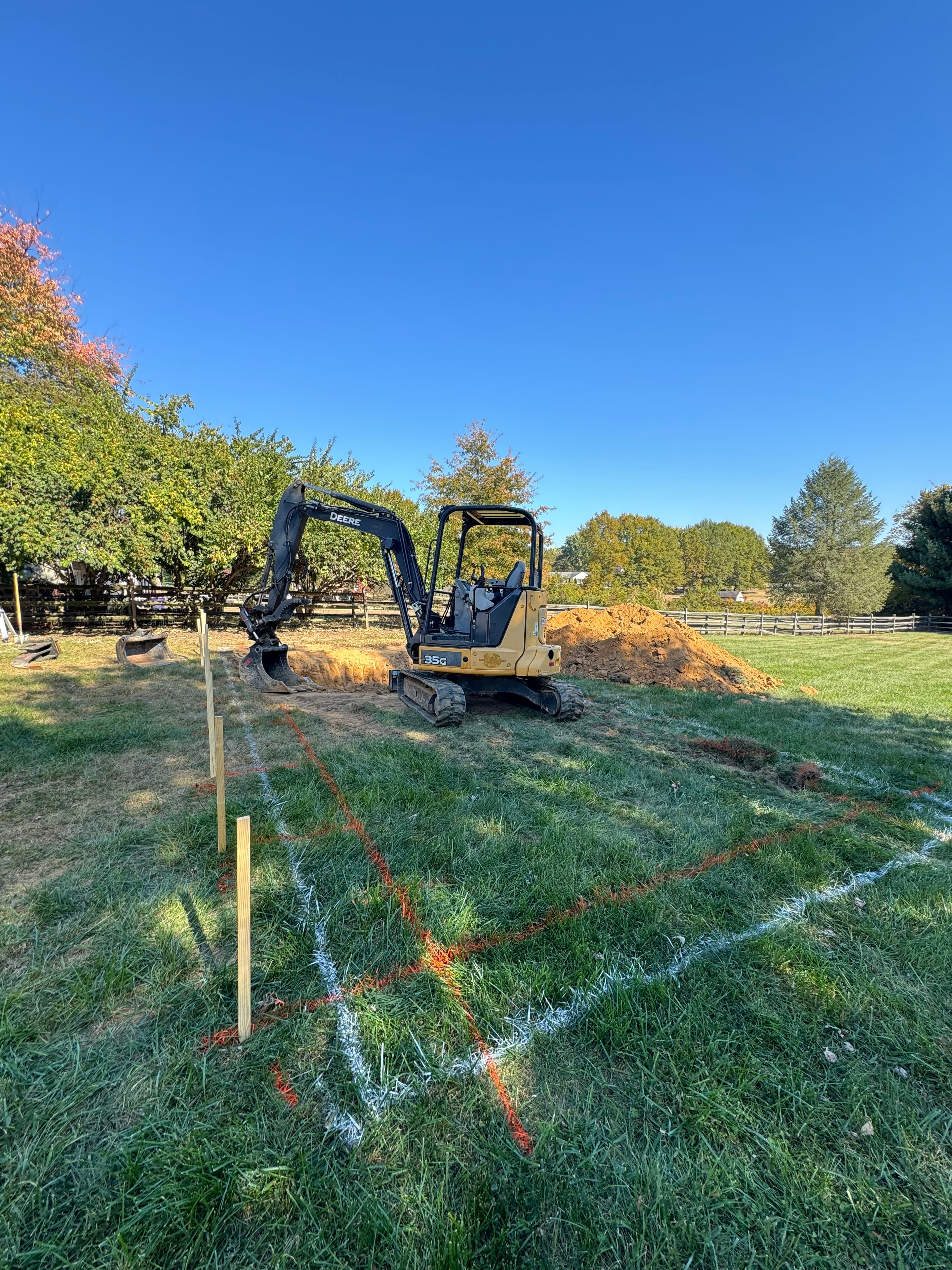 Under construction — John Deere mini excavator on site with pool area staked out