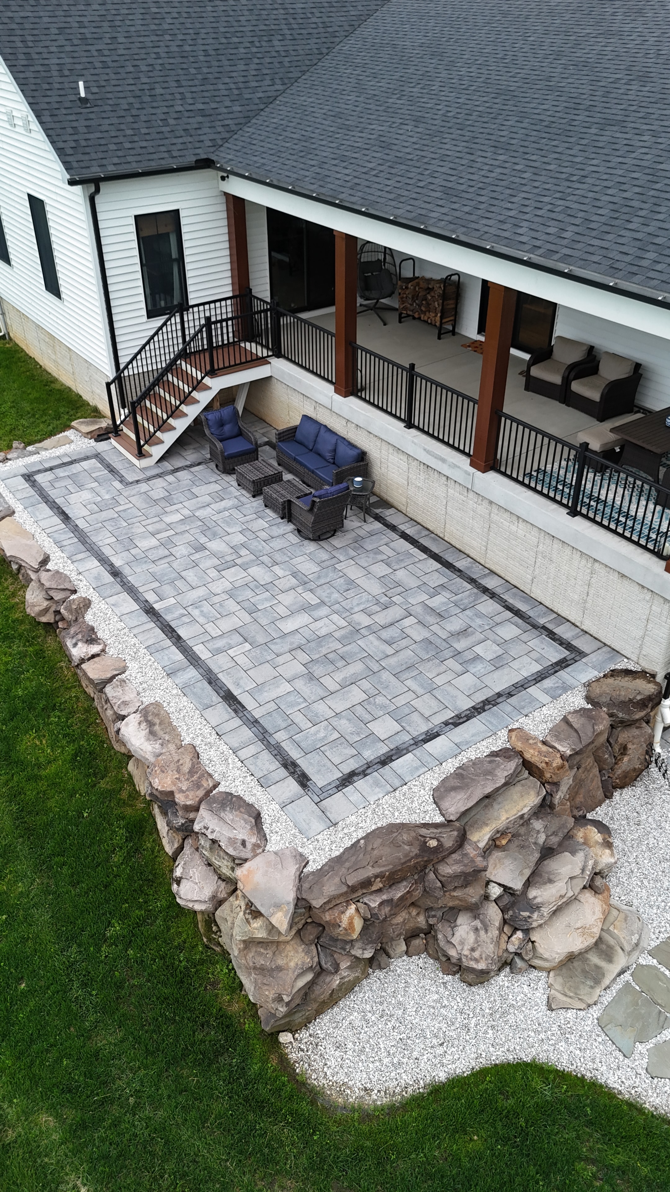 Country Oasis — aerial view of paver patio with rock border and deck stairs