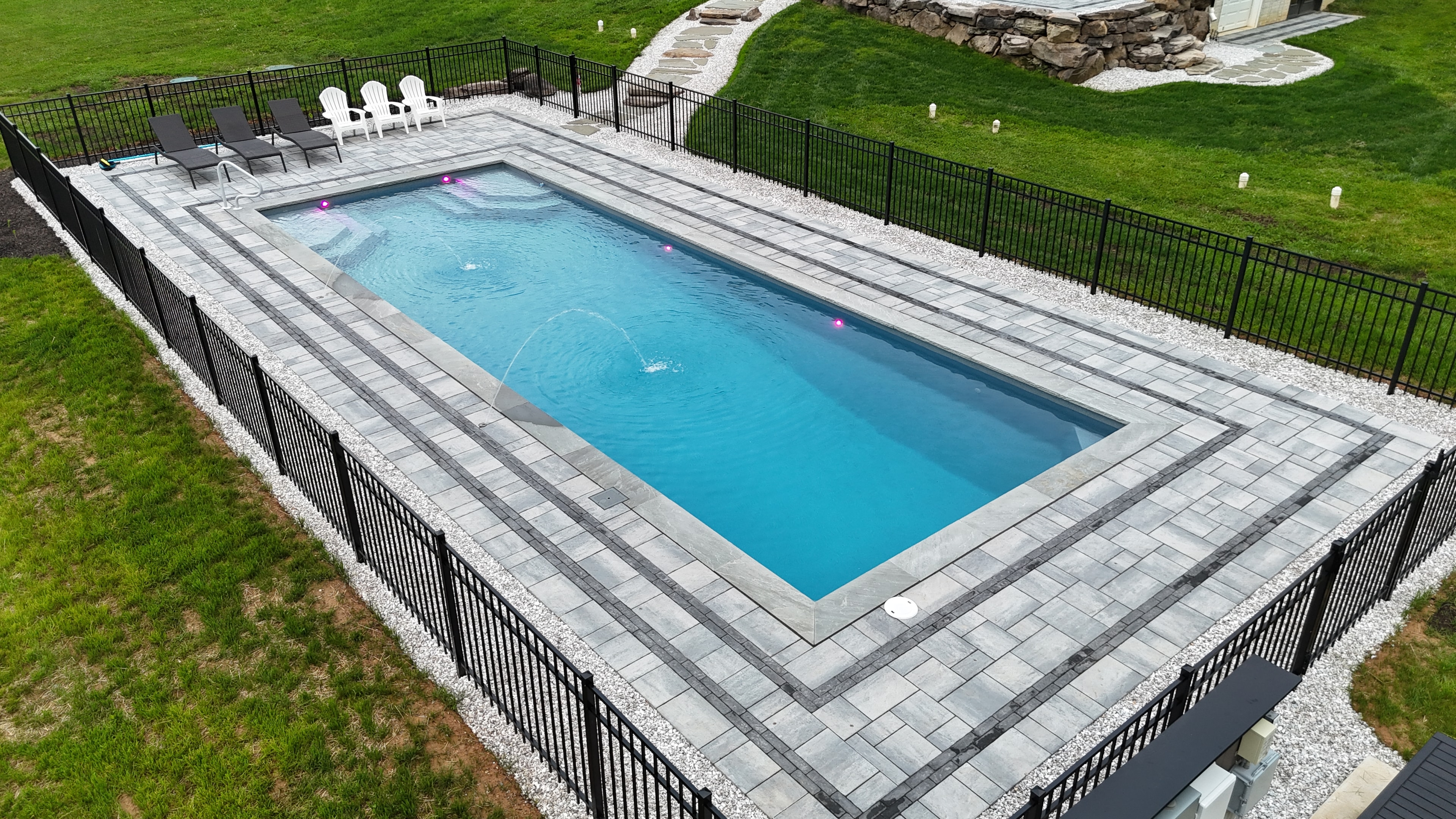 Country Oasis — ground-level view of pool with paver surround and fountain jets