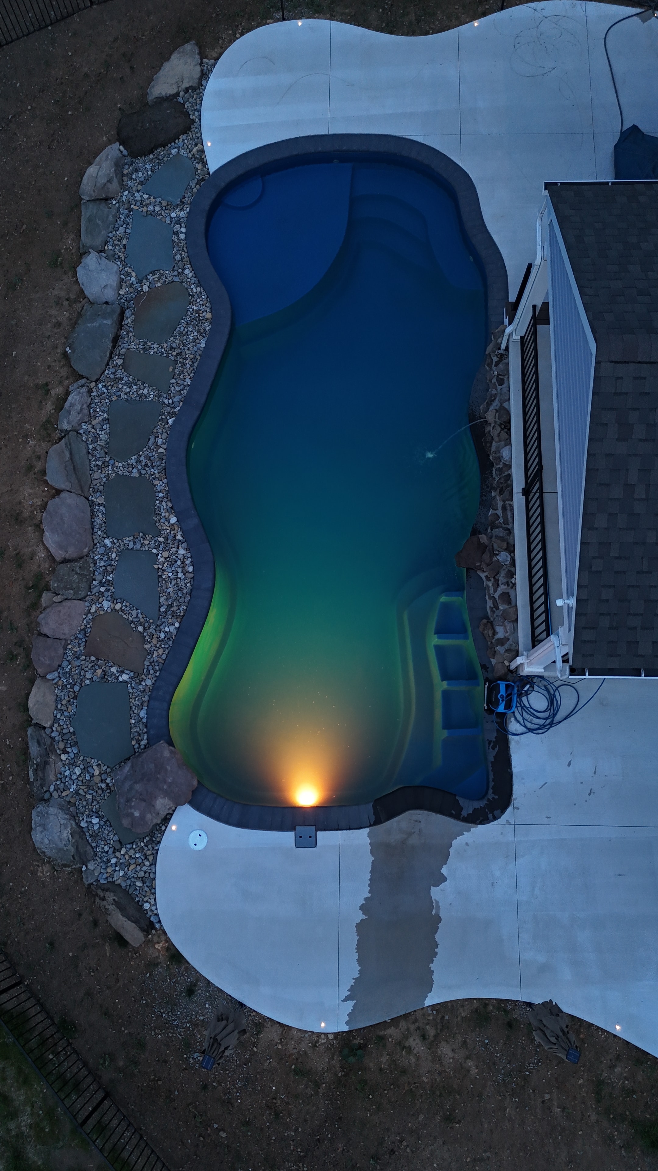 Tight Quarters — ground-level sunset shot of pool with concrete patio, pergola, and soft evening sky